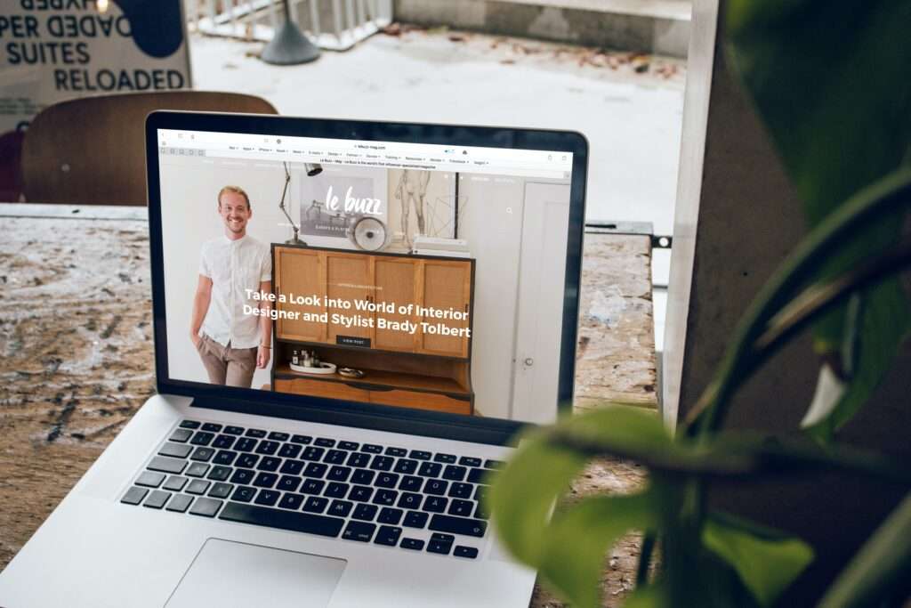 laptop on a desk open to a stylist/s webpage and a plant next to it