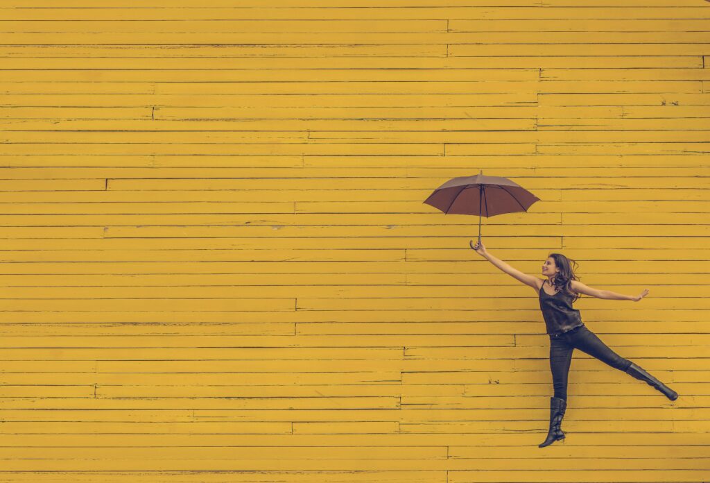 woman with open umbrella in front of a yellow wall. nonprofit brand alignment